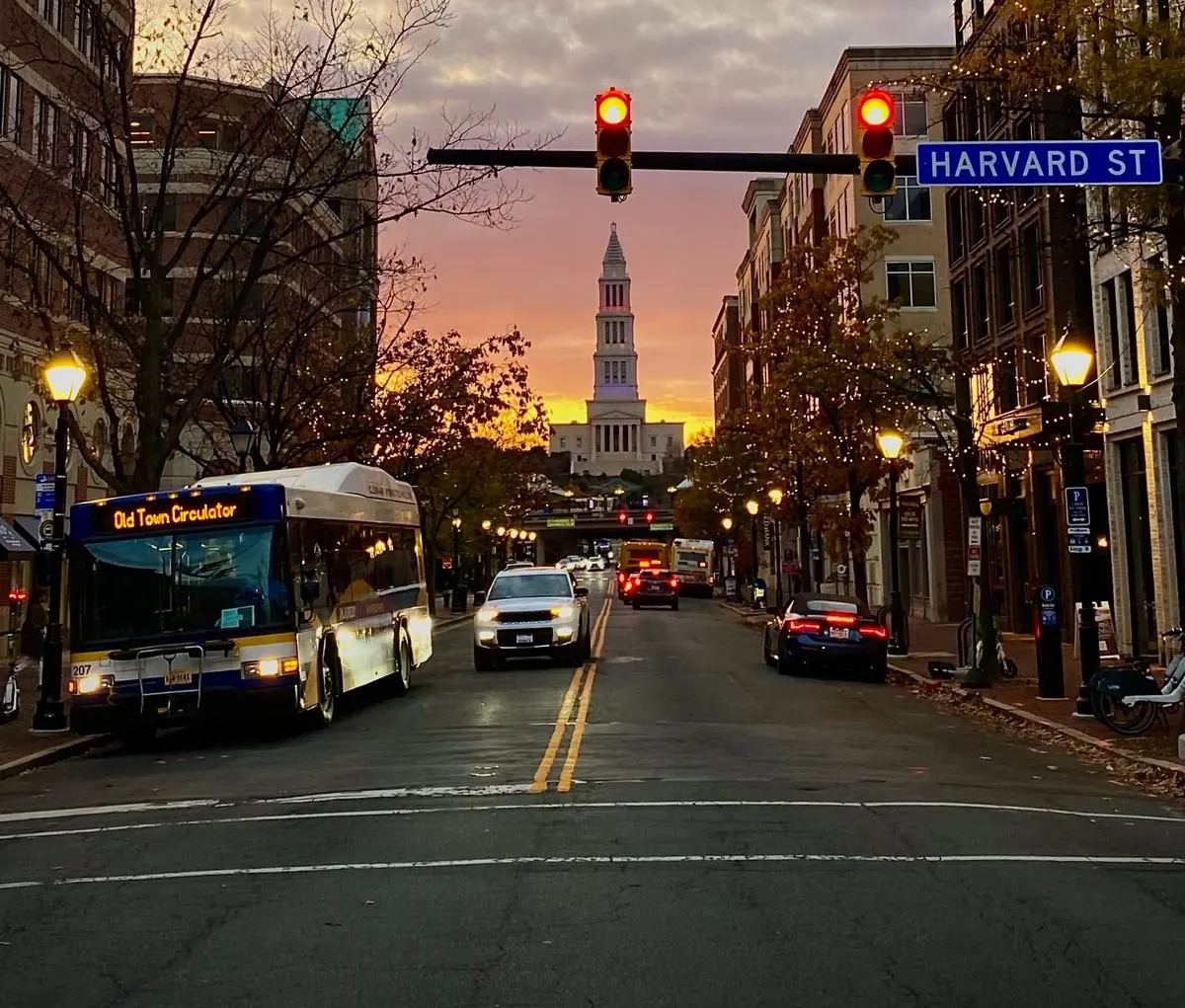 Old Town Circulator bus on Harvard Street in Alexandria, Virginia at sunset, with the George Washington Masonic National Memorial visible in the distance