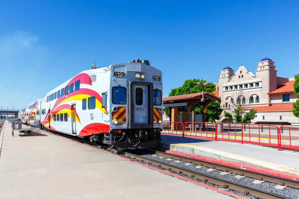 New Mexico Rail Runner Express commuter train at Downtown Albuquerque station, with the historic Spanish Colonial Revival station building in the background