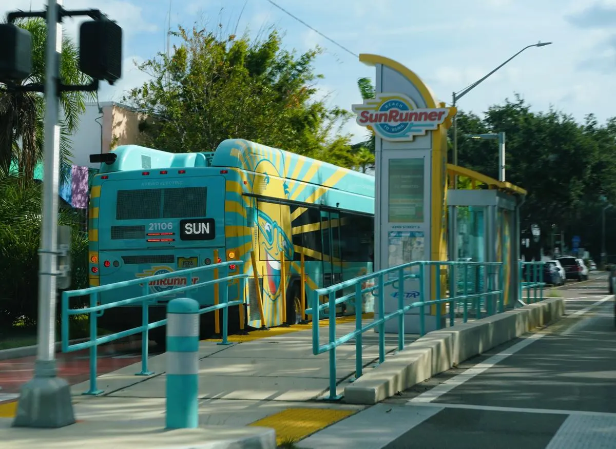 SunRunner hybrid-electric bus docked at a station with teal railings in St. Petersburg, Florida